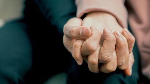 A color photo of a close up of two people holding hands. Photo taken by Sơn Bờm. 