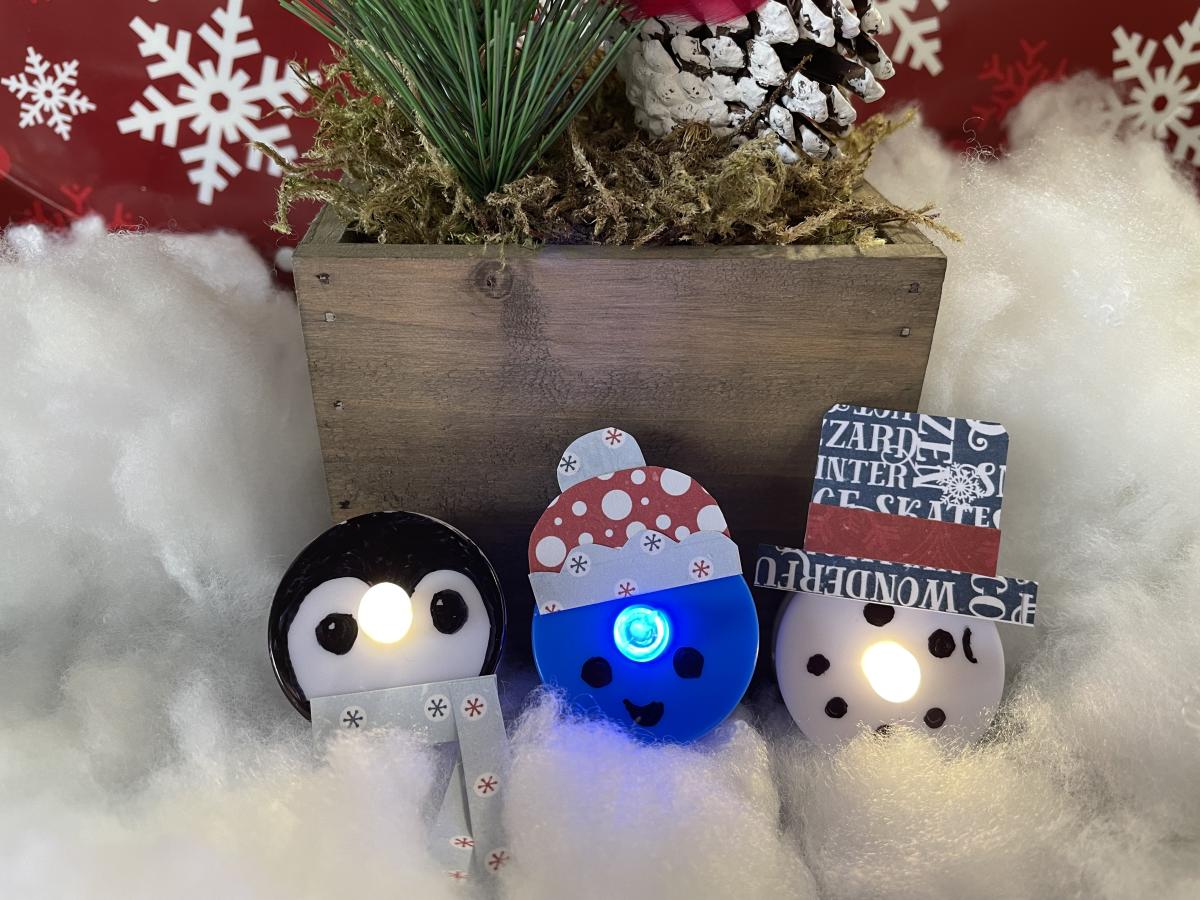 Three pins made of battery-powered tea-lights: a penguin, a narwhal, and a snowman.